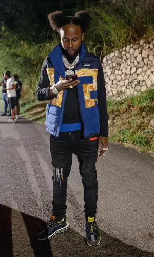 Popcaan wearing Versace jacket