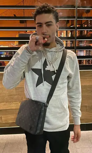 Jay Critch’s Outfit in Amiri Jeans, Prada Sneakers & Louis Vuitton Bag (2022)